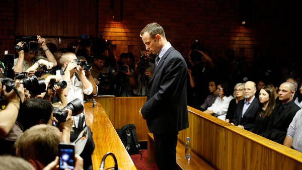 Oscar Pistorius stands at the dock before the start of proceedings at a Pretoria magistrates court